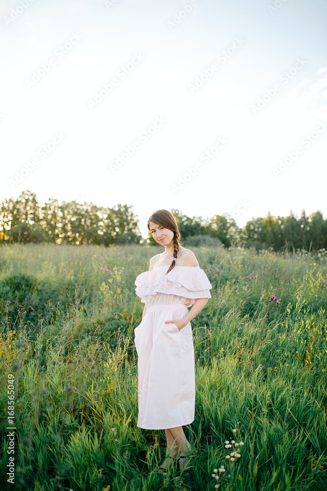 Beautiful girl walking on the grass field on the evening sun Beautiful girl walking on the grass field on the evening sun
