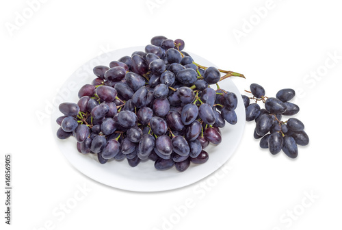 Clusters of blue grapes on a white dish and beside