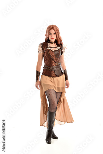 full length portrait of a red haired lady, wearing a steampunk inspired outfit, isolated on white background.