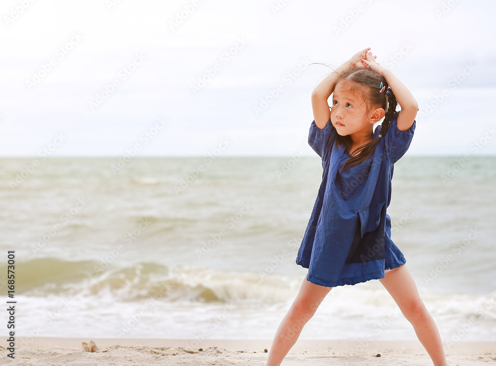 Little asian girl poses and relax on the beach.