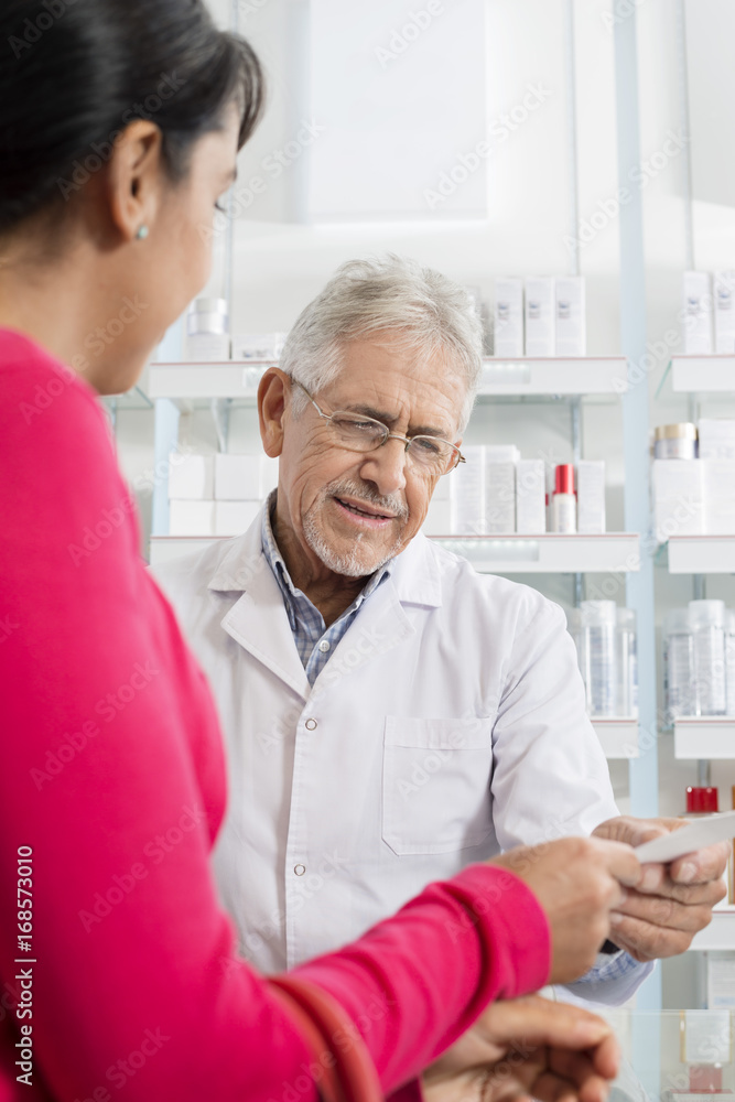 Fototapeta premium Woman Showing Prescription To Chemist In Pharmacy