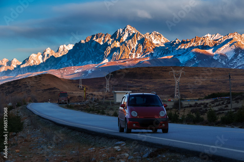 Journey of a red car on the road with Landscape View snow of Mountain in the winter season.