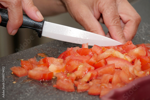 woman cutting tomato with the knife, on a plate
