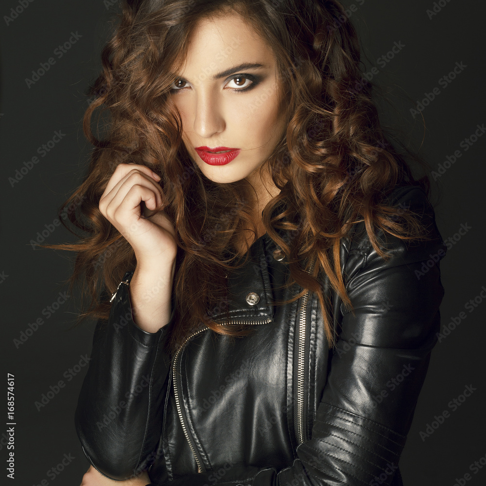 Beautiful young woman posing in black leather jacket over grey background. Fashion concept. Beautiful young woman posing in black leather jacket over grey background. Fashion concept.