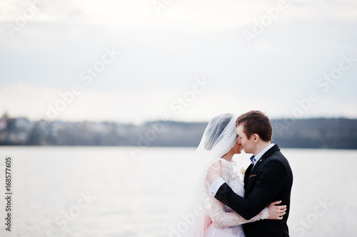 Close-up photo of a kissing wedding couple on the lakeside. © AS Photo Family