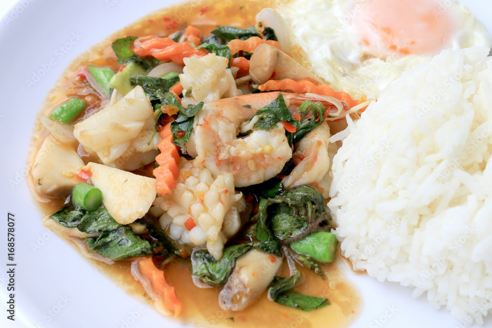 Asian food, Stir fried seafood with chili paste and basil leafs with rice on white plate, Spicy hot chilli Thai food. Asian food, Stir fried seafood with chili paste and basil leafs with rice on white plate, Spicy hot chilli Thai food.