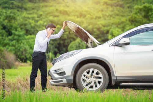 Billede på lærred Full length of worried businessman by broken down car at countryside, man beside