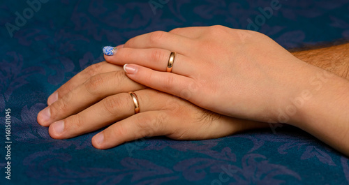 Photo of hands with beautiful wedding rings on blue background