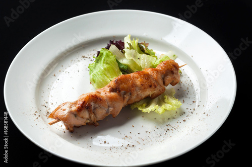 chicken kebab on a skewer with garnish and sauce 