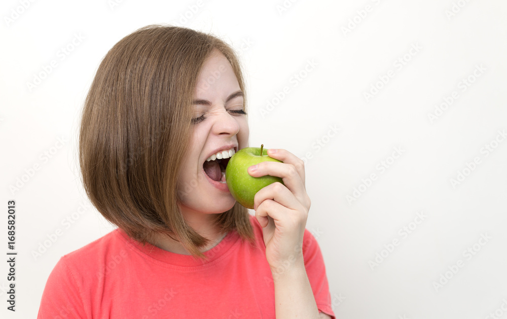 Portrait of girl with bob hairstyle biting green apple as if suggesting healthy life, fruit diet or tasty apple. White background Portrait of girl with bob hairstyle biting green apple as if suggesting healthy life, fruit diet or tasty apple. White background