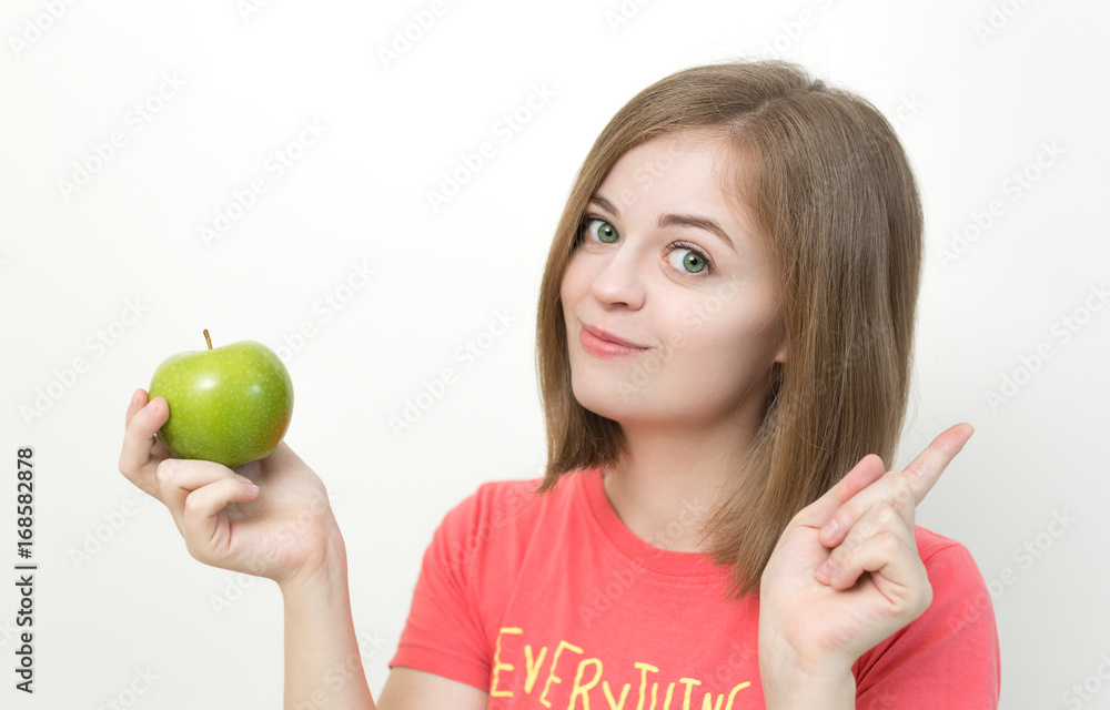Portrait of smiling pretty girl with bob hairstyle and green apple in her hands as if suggesting healthy life, fruit diet or tasty apple. White background Portrait of smiling pretty girl with bob hairstyle and green apple in her hands as if suggesting healthy life, fruit diet or tasty apple. White background