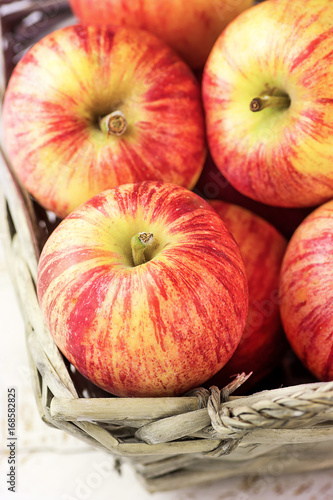 Heap of ripe organic red striped apples in a wicker basket. Whit