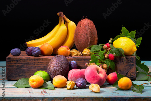 Fruit bunch with coconut, Mango, peaches, apricots, lemons, physalis, plums on the colorful wood background