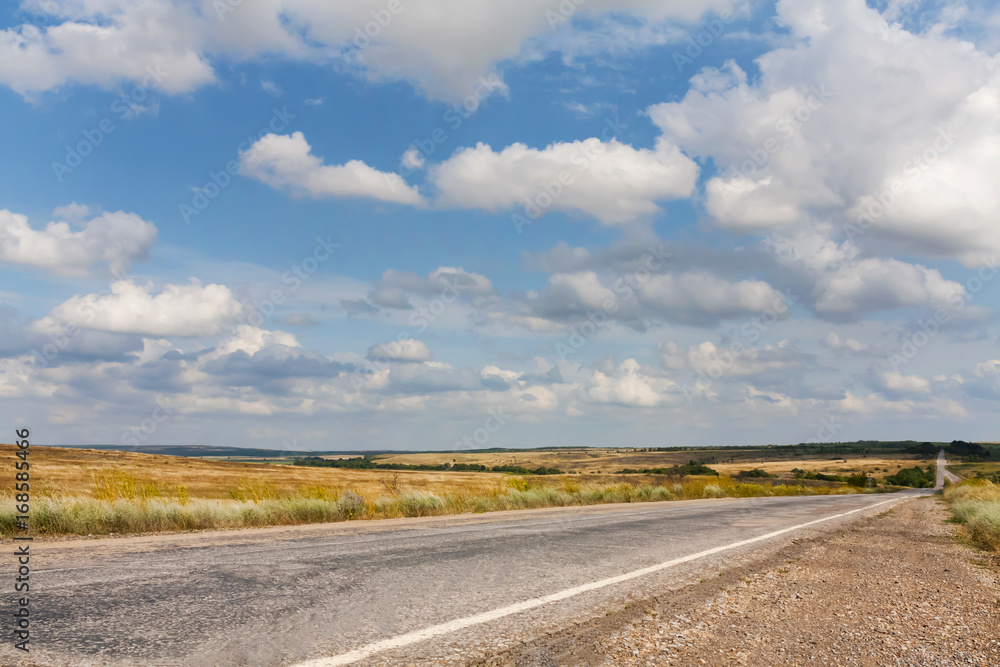 Old road in the Ukrainian steppe in summer under blue sky with clouds Old road in the Ukrainian steppe in summer under blue sky with clouds
