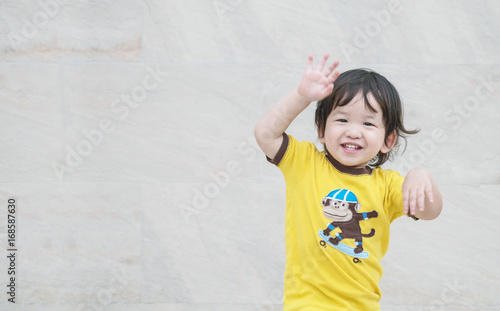 Closeup enjoy asian kid with smile face on marble stone wall textured background with copy space