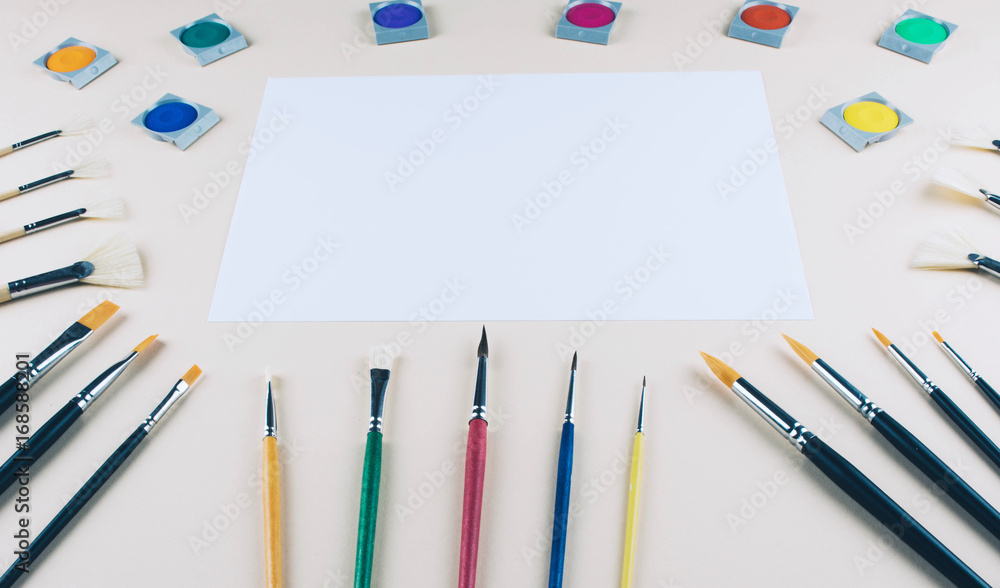 Watercolor and brushes at beige background. Watercolor and brushes at beige background.
