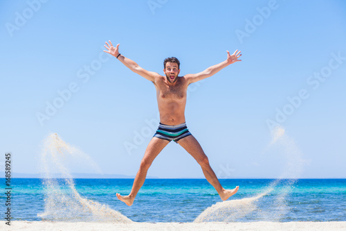 Happy young man jumping at the beach