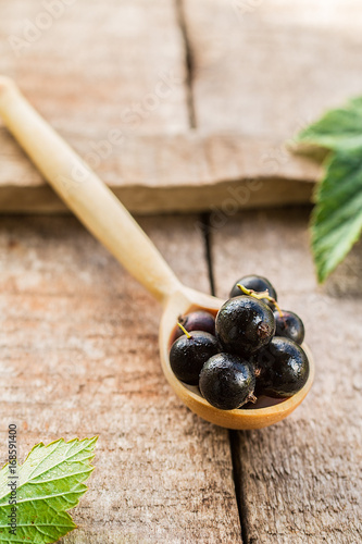  black currant in wooden spoons on wooden background