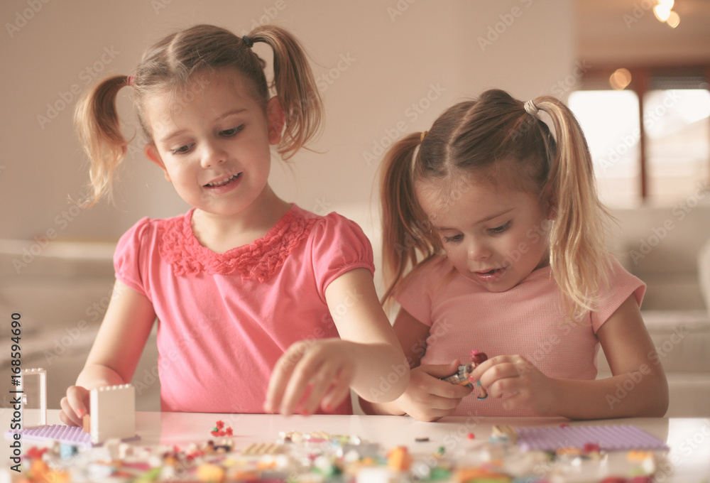 Fototapeta premium Girls playing at home. Girls playing with Bricks at home.