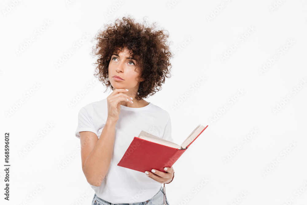 Pensive young woman holding book and looking away Pensive young woman holding book and looking away