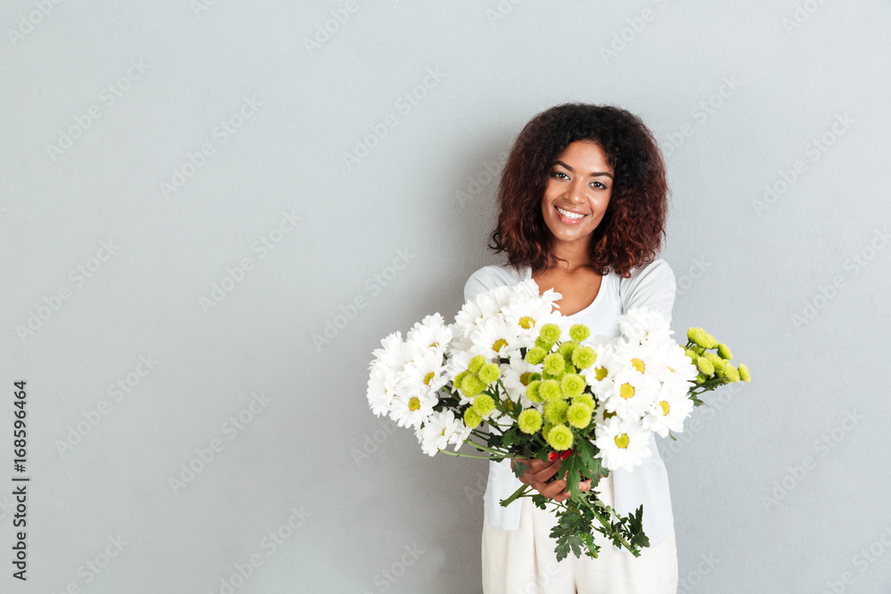 Attractive young african woman giving flower bouquet to camrera Attractive young african woman giving flower bouquet to camrera