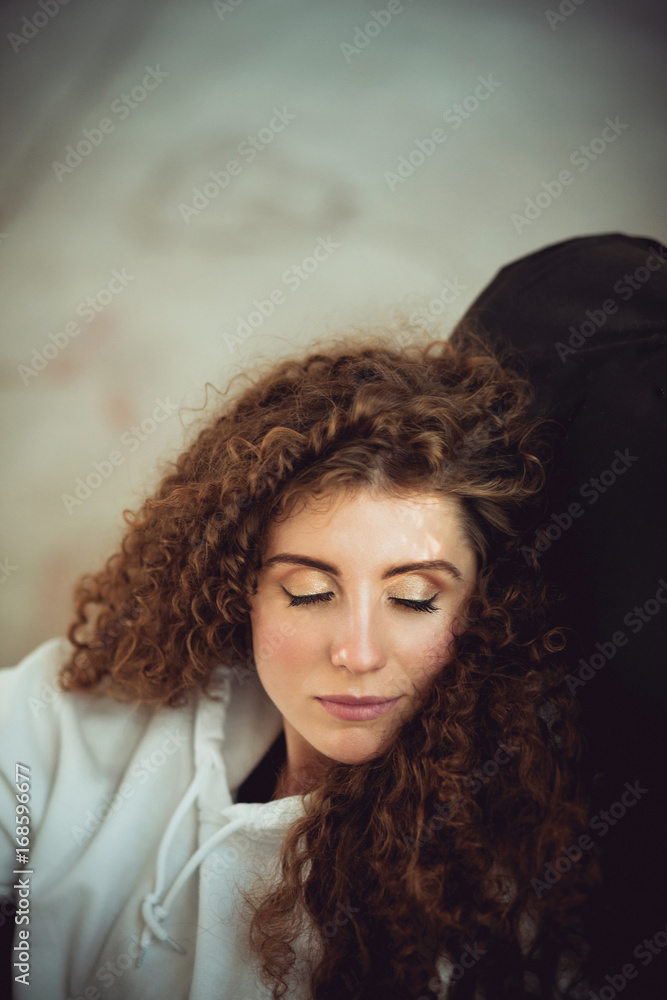 Beautiful stylish woman with curly hair in white sweatshirt