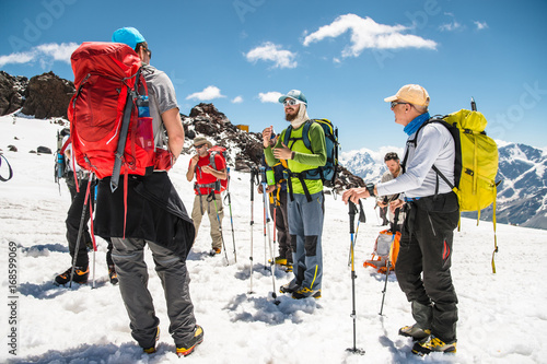 A team of climbers led by a guide discusses the upcoming ascent
