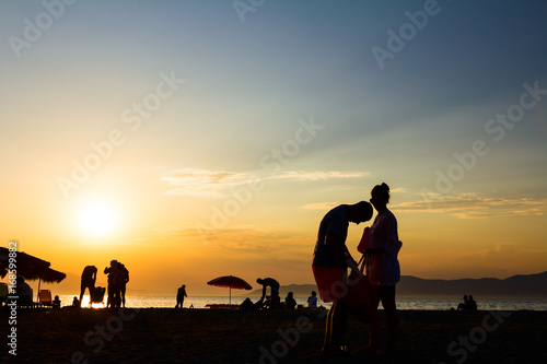 Silhouetted shot of sunset with people by the beach
