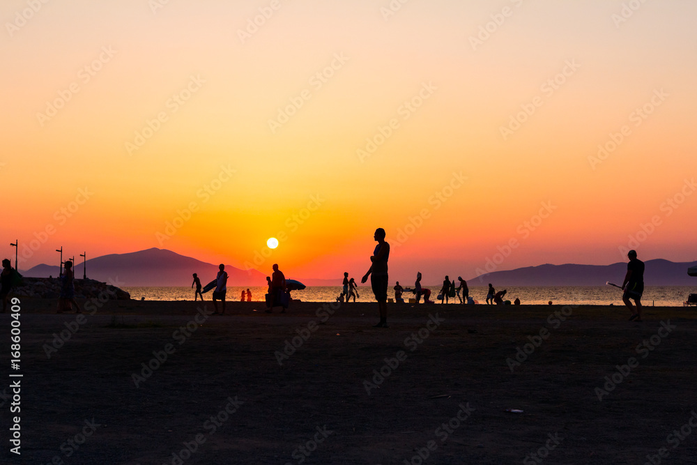 Silhouetted shot of sunset with people by the beach