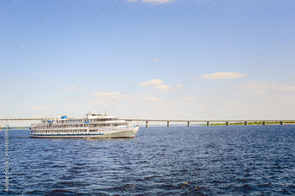 A three-deck motor ship floats along the river.