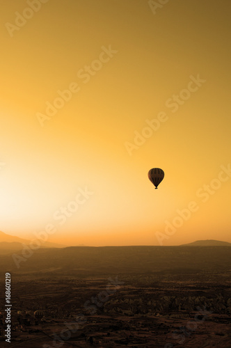 ballooning. A balloon flies in the sky in the rays of the rising sun. A bright sky, a haze, an extinct volcano on the horizon.