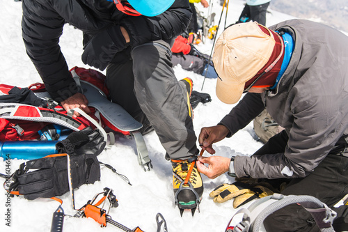 Obraz na plátně A professional guide helps you set up and dress alpinist crampons