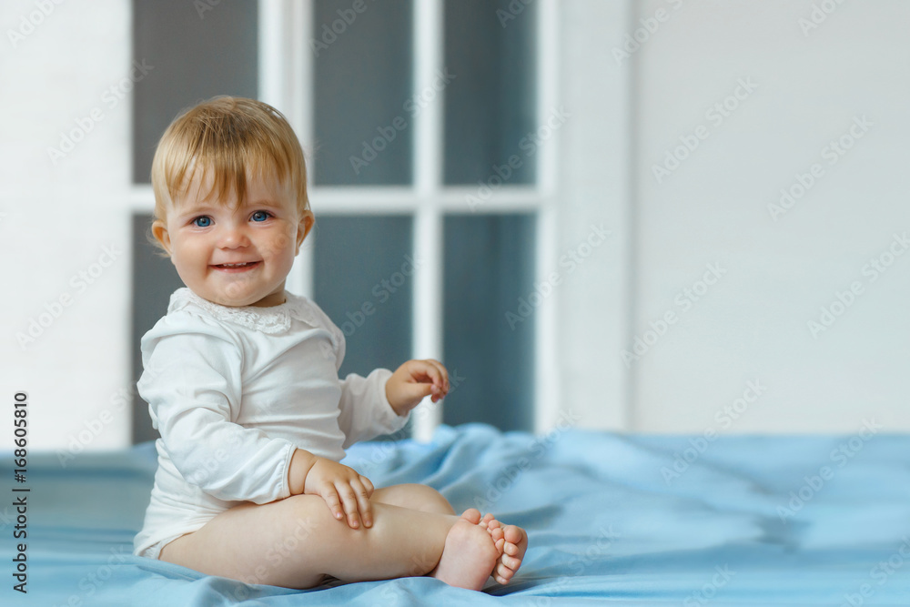 Smiling baby girl sit on the bed