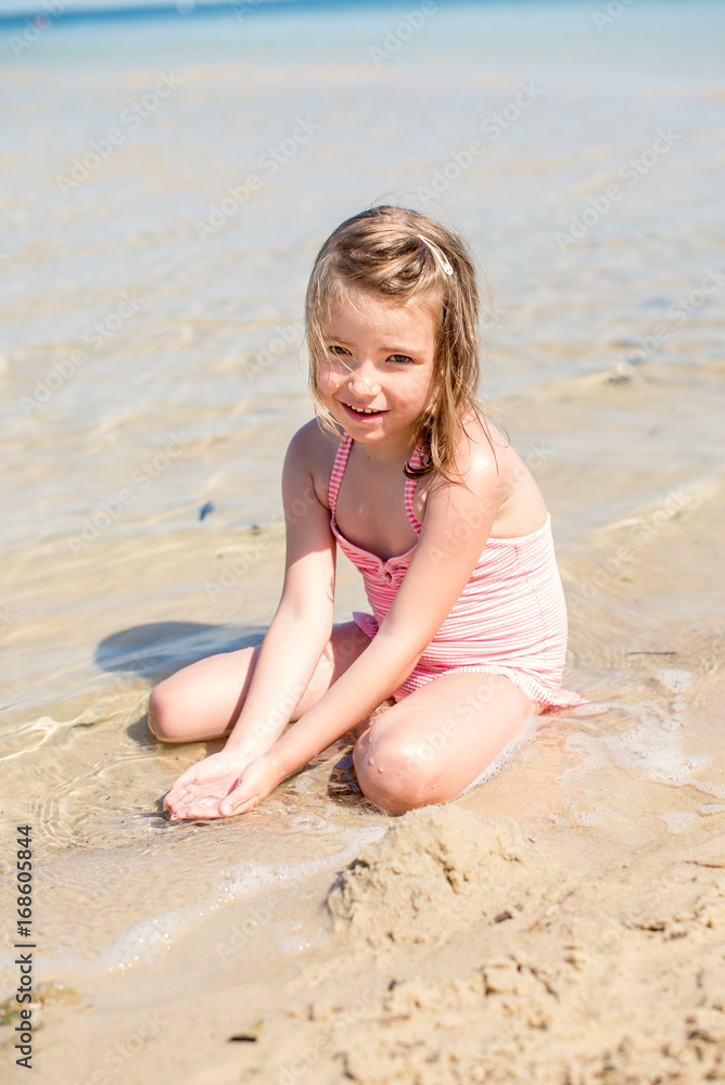 Pretty little girl playing with sand on the beach. Summer time Pretty little girl playing with sand on the beach. Summer time