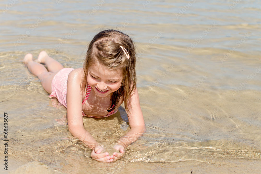 Cute girl laying in the sand on the beach