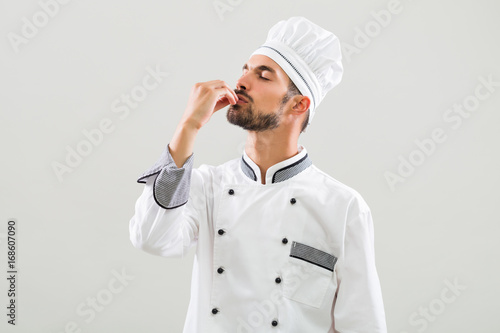 Chef is showing delicious sign on gray background. photo