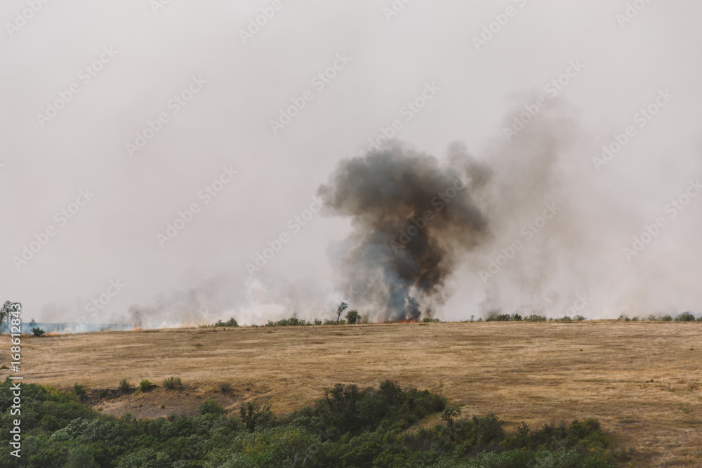 Black smoke from wildfire or natural fire in yellow fields in Rostov region