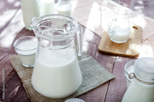 jug of milk and glasses of milk on a wooden rustic table.