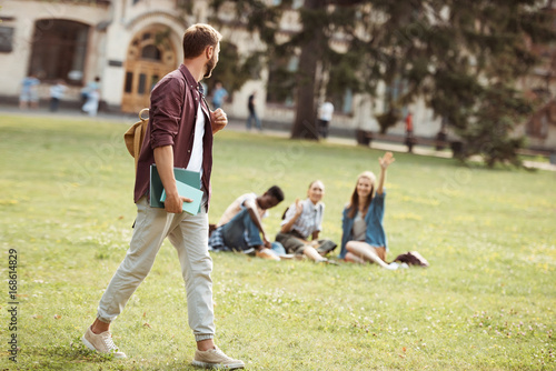 student with books looking at classmates