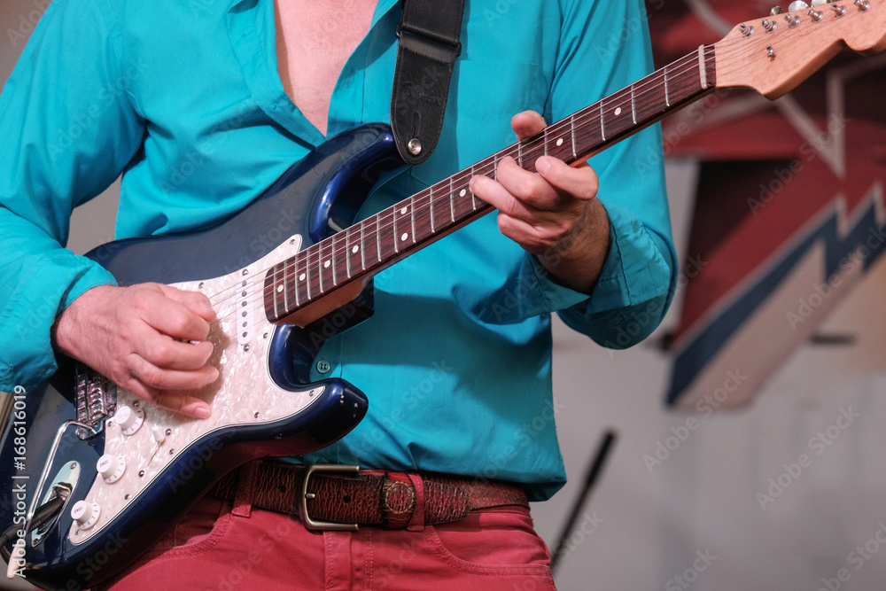 musician guitarist in red jeans and a blue shirt