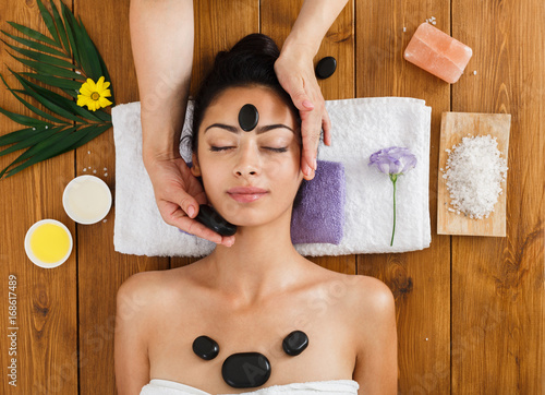 Beautician make stone massage spa for woman at wellness center