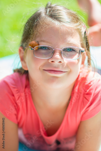 Smiling happy child girl in glasses outdoors