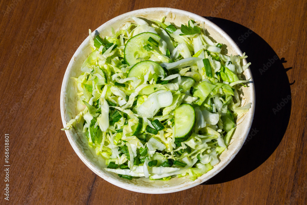 Spring vegan salad with cabbage, cucumber, green onion and parsley on wooden table Spring vegan salad with cabbage, cucumber, green onion and parsley on wooden table