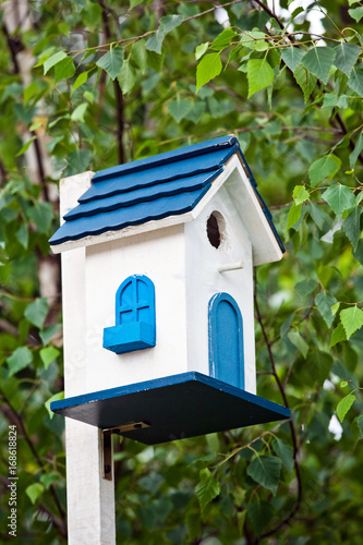 Blue birdhouse on the tree. Wooden house for birds among the leaves