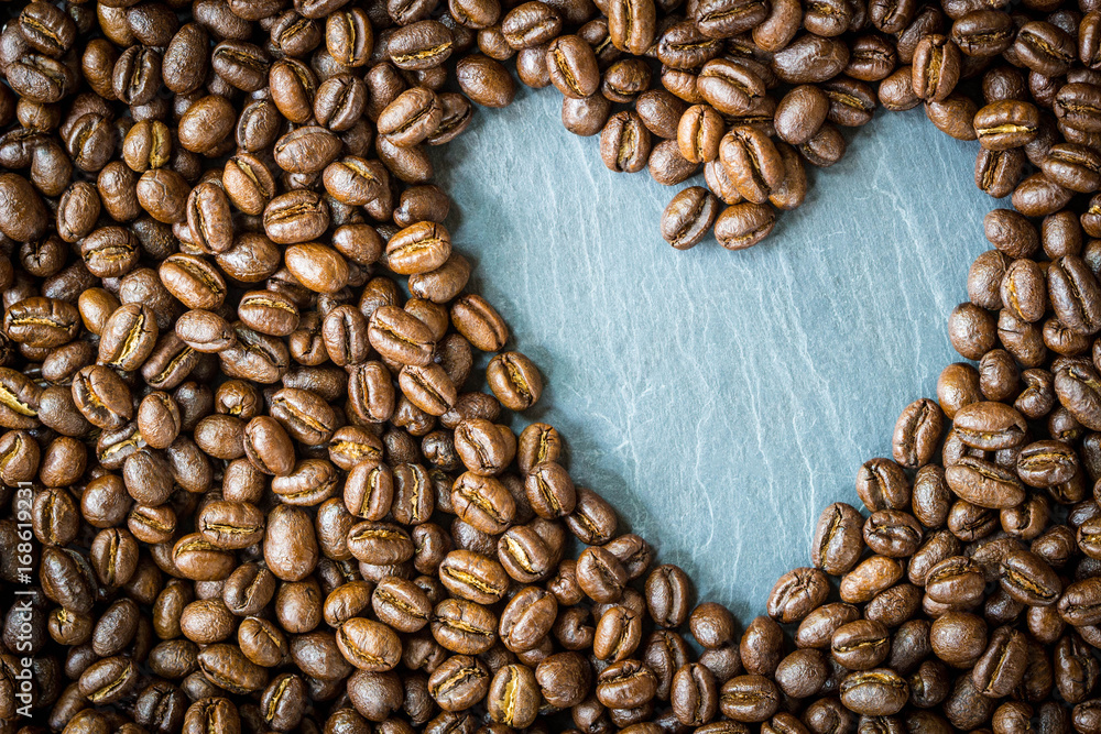Pea berry coffee beans with heart shape on stone plate , top view and copy space Pea berry coffee beans with heart shape on stone plate , top view and copy space