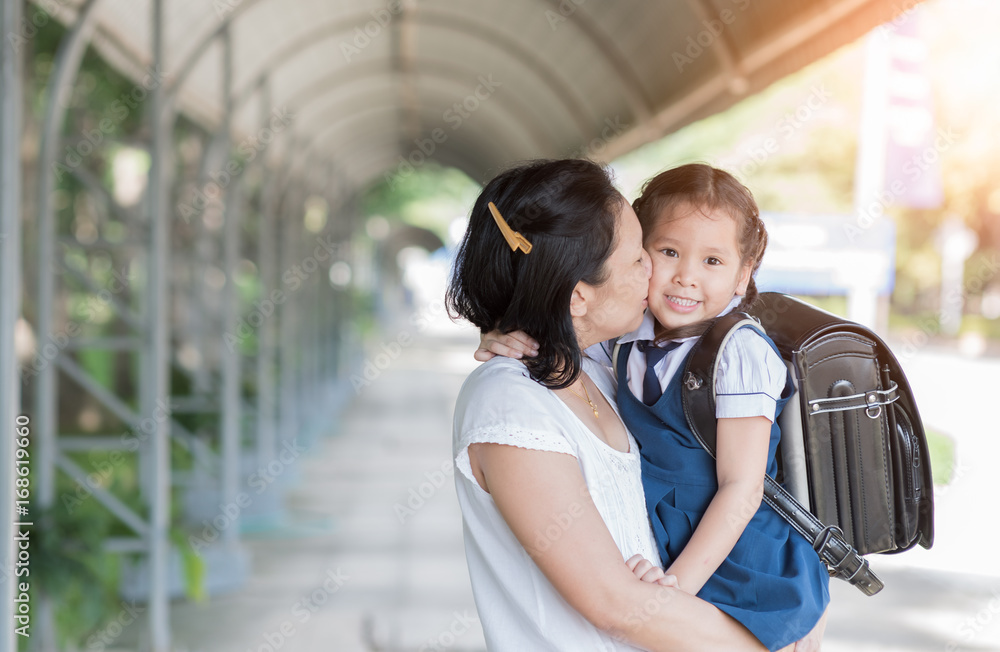 Mother kissing schoolgirl in uniform.