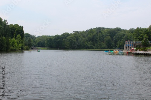 The boats and the lake at the park on a sunny humid day.