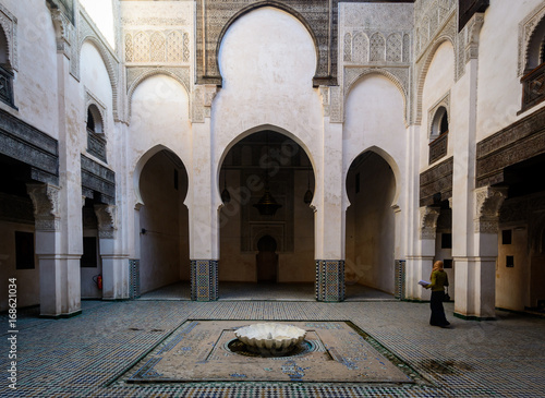 A woman inside an Inner Yard (Riad) with colorful tiles on the floor, Morocco
