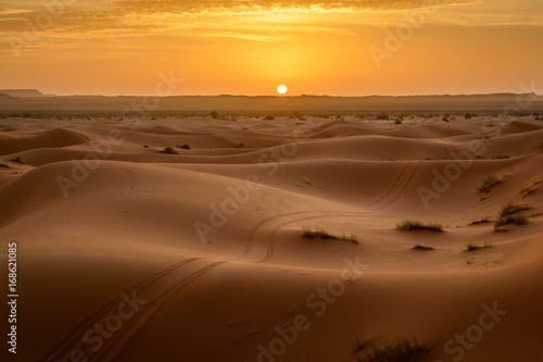 Sunrise at Erg Chebbi sand dune of Sahara with ATV tyre markings on the sand  Merzouga  Morocco