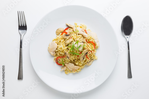 Stir-fry noodles with chicken meat, mushroom and red capsicum in a plate on white background top view
